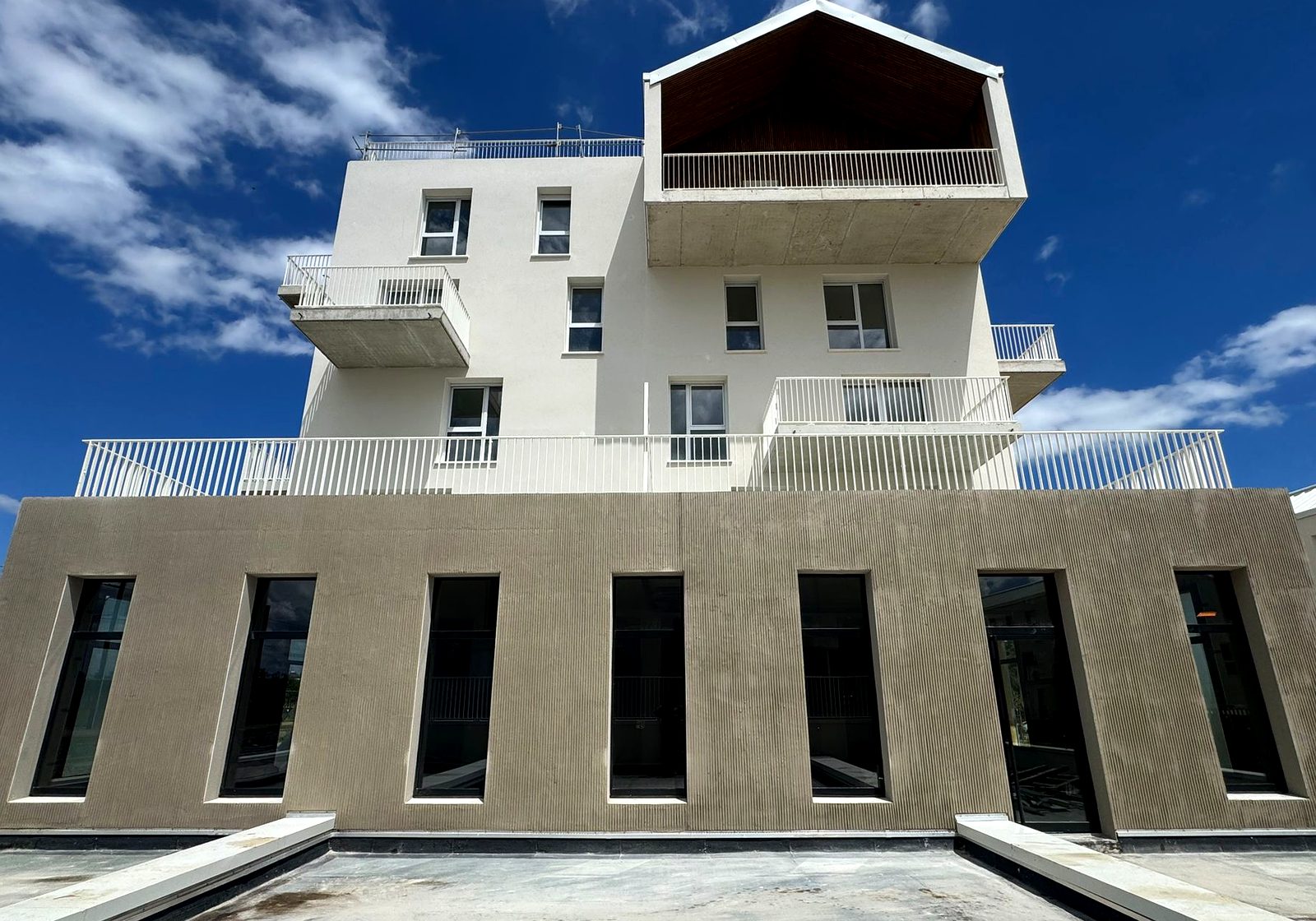 Ravalement de façade d'un immeuble collectif : enduit peigné en soubassement et façade claire à l'étage